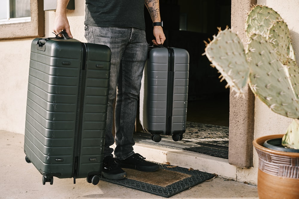 A traveler carrying packed suitcases out the door